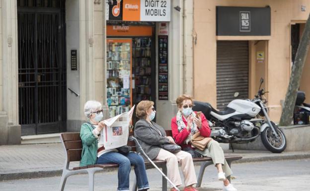 Unas mujeres conversan en un banco. 