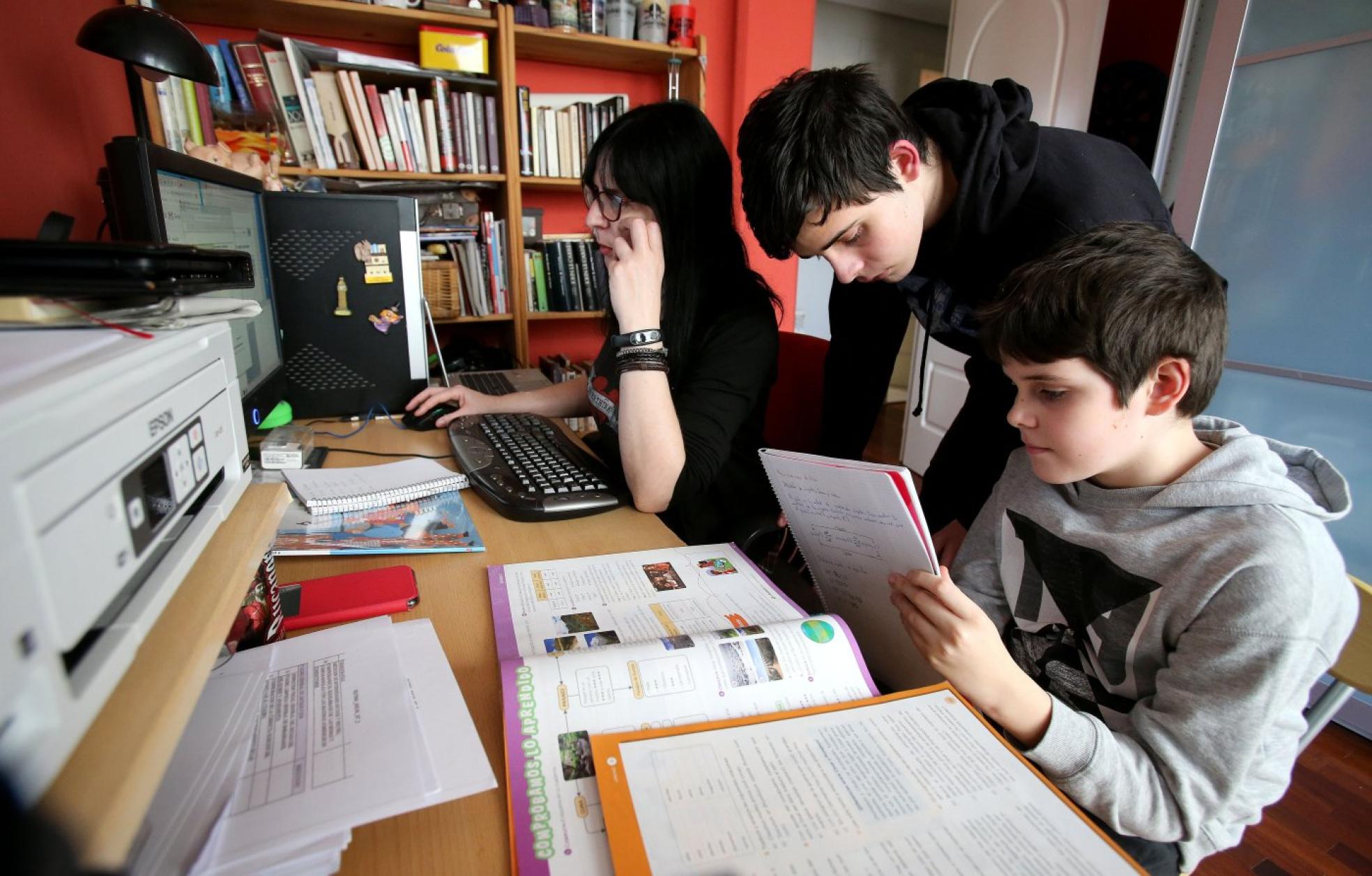 Una madre 'teletrabaja' mientras sus hijos hacen las tareas escolares. 