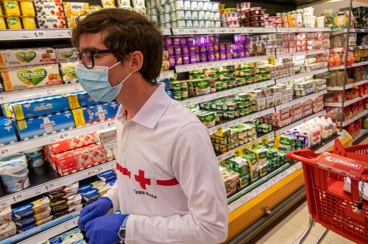 Un vountario compra para personas mayores en un supermercado de Zaragoza. 