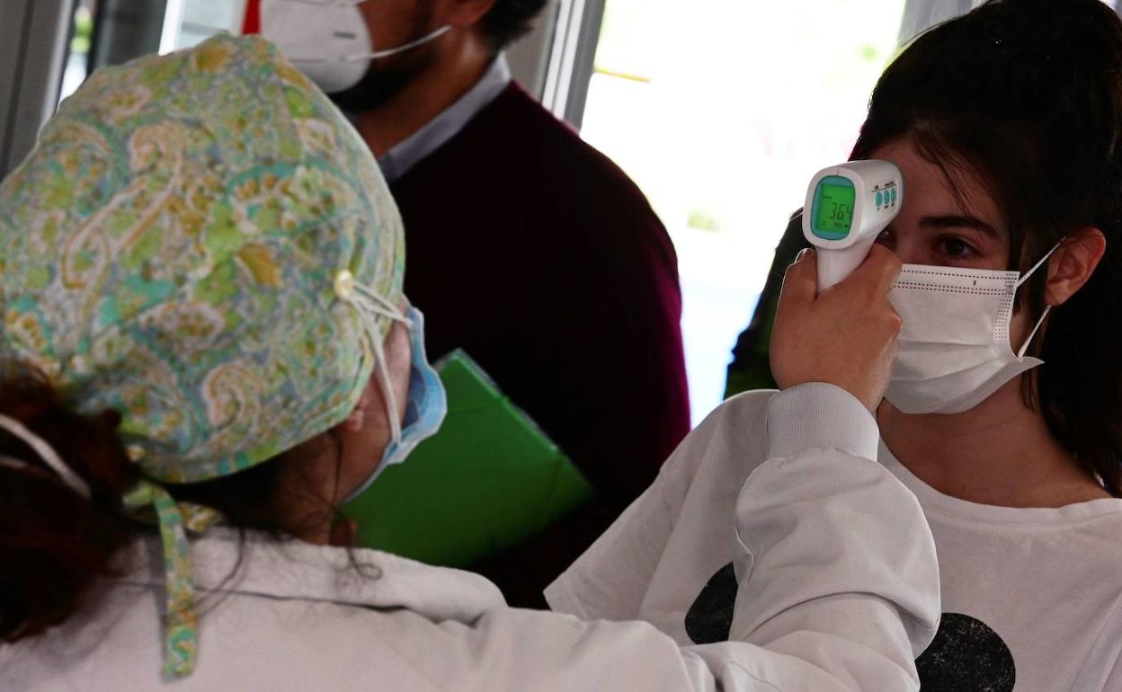 Un sanitario toma la temperatura a una mujer que accede al Hospital de Alcorcón. 