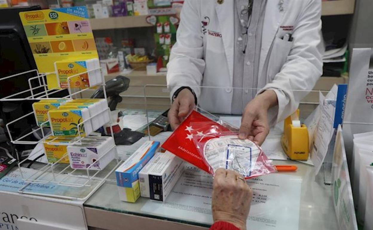 Un farmaceútico entrega a un cliente una mascarilla FFP2 modelo KN95 