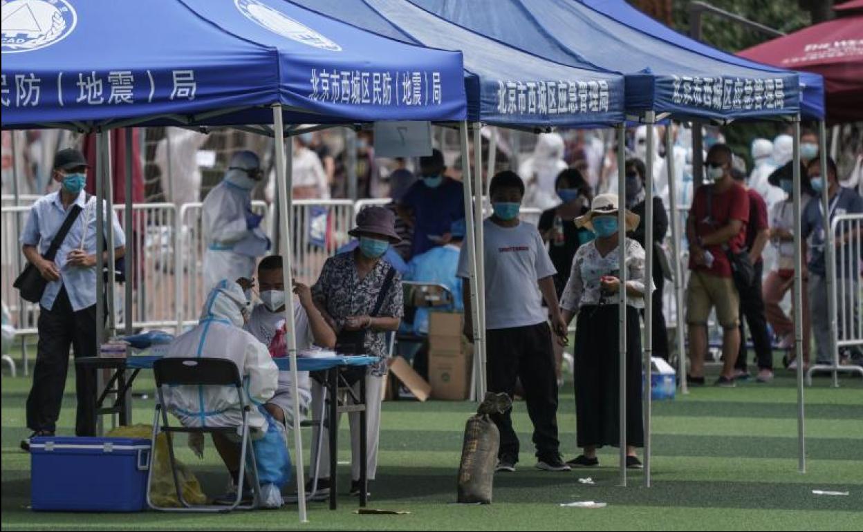 Residentes o gente que visitó el mercado de Xinfadi hacen cola para hacerse el test de coronavirus en el pabellón deportivo de Guang'an, en Pekín. 