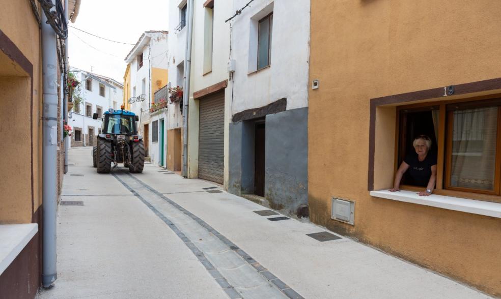 Una mujer se asoma a la ventana de su domicilio en Medrano tras el paso de un tractor por la calle vacía. 