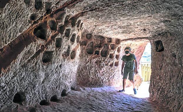 Imagen principal - El camino hacia las 'cuevas del ajedrezado' y la entrada a una de las grutas horadadas en la piedra en Santa Eulalia Somera; y panorámica del pueblo desde el barrio de las bodegas; 