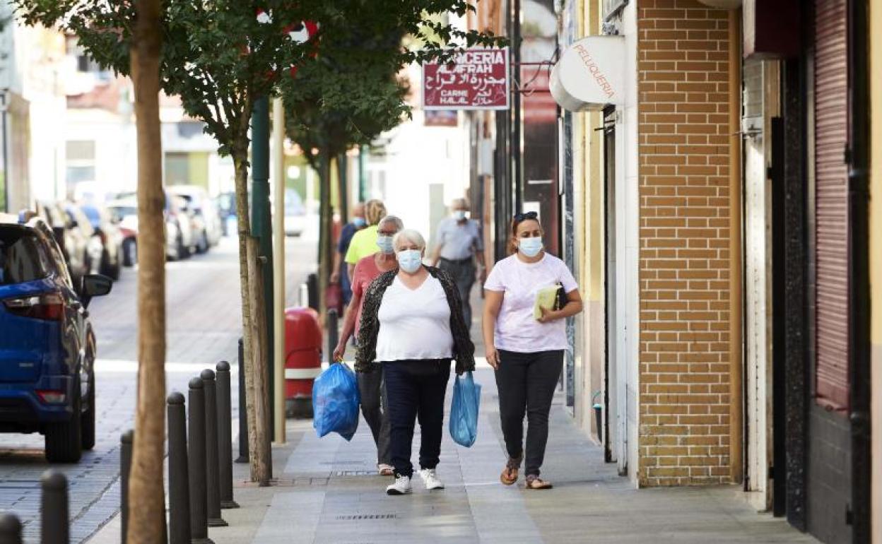 Transeúntes pasean por las calles del barrio La Inmobiliaria de Torrelavega, en Cantabria