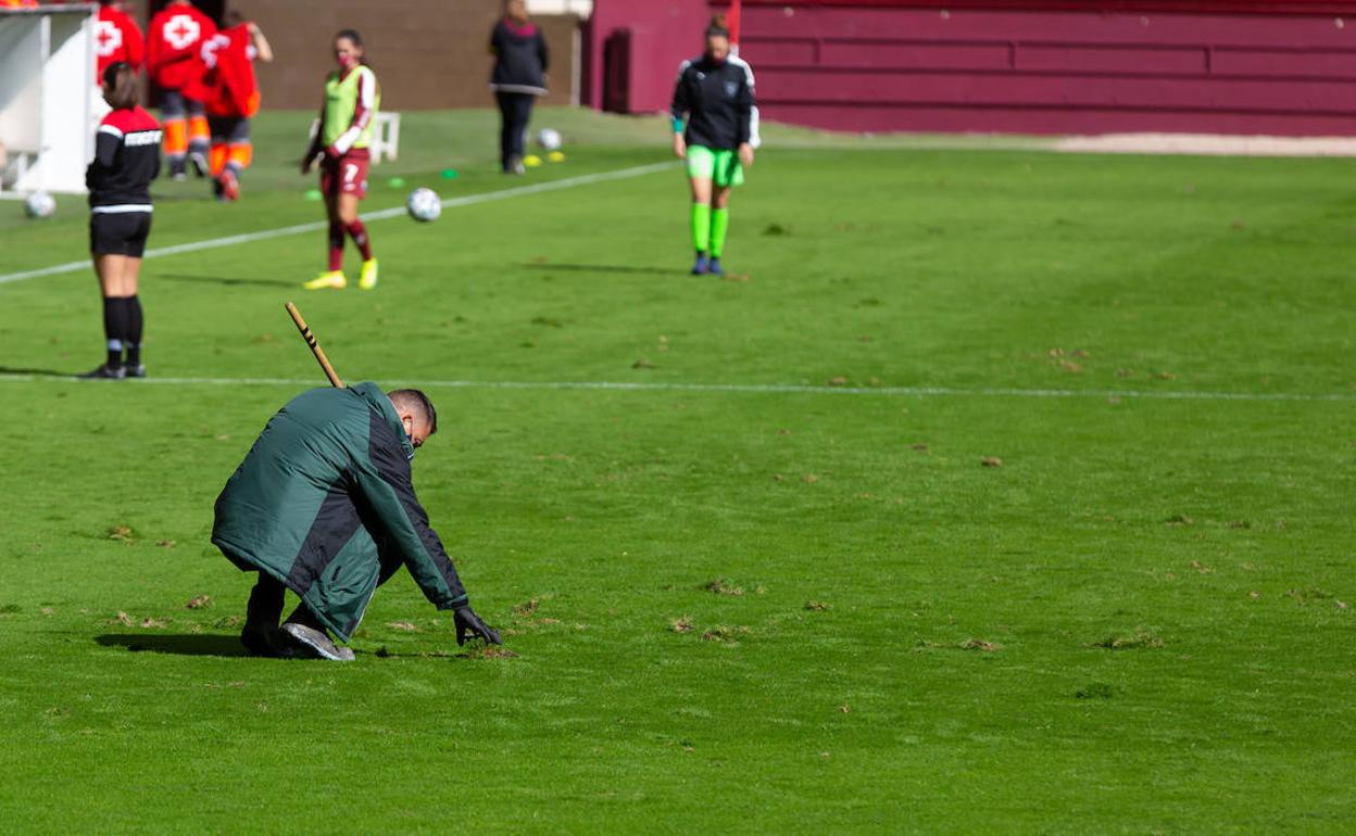 Un operario arregla los baches del césped en el descanso.