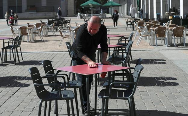 Un hostelero limpia una mesa en la Plaza Mayor de Leganés.