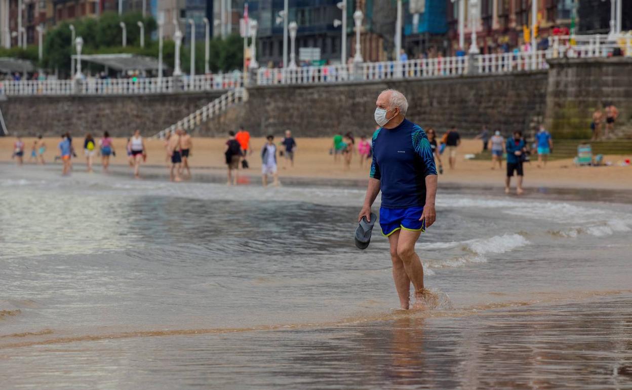 Paseantes por la playa de Gijón, Asturias.