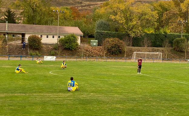 Los jugadores del Alberite, sentados, y lo del Náxara con la boca tapada al comenzar el partido en el Sáenz Andollo. 