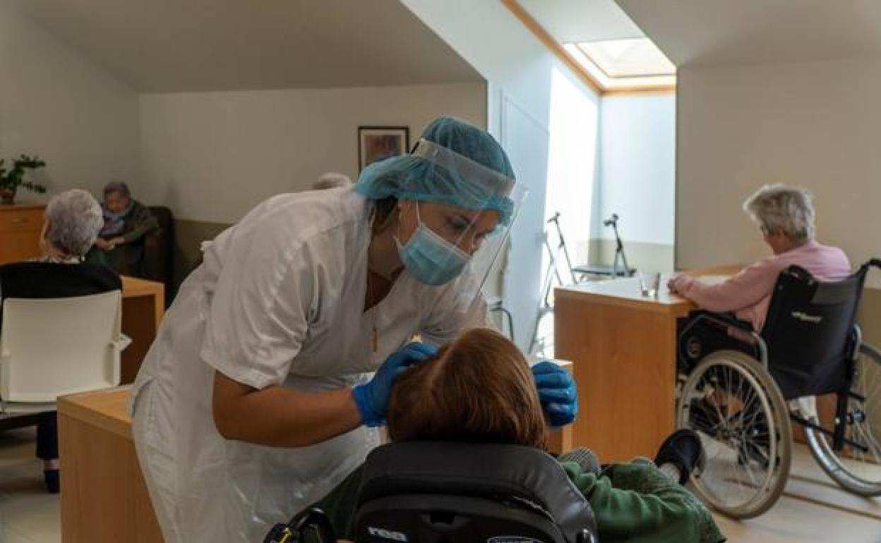 Una enfermera hace una prueba de covid a una persona mayor en una residencia. 