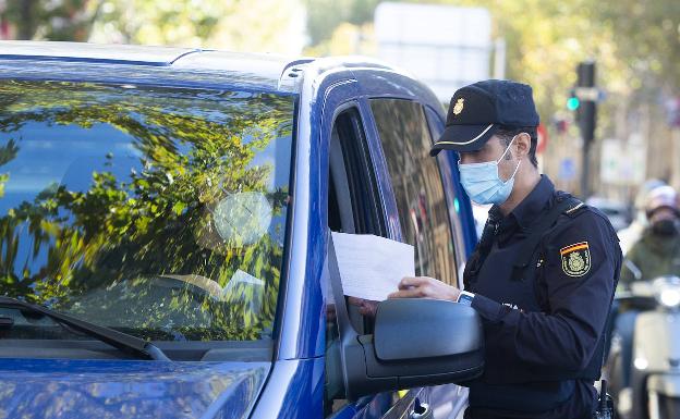 Un policía comprueba la autorización de un conductor para poder circular durante la pandemia