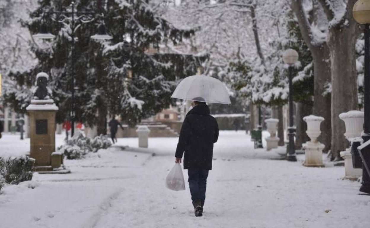 Un hombre pasea con paraguas por la nieve tras el paso de la borrasca Filomena, en Huesca.