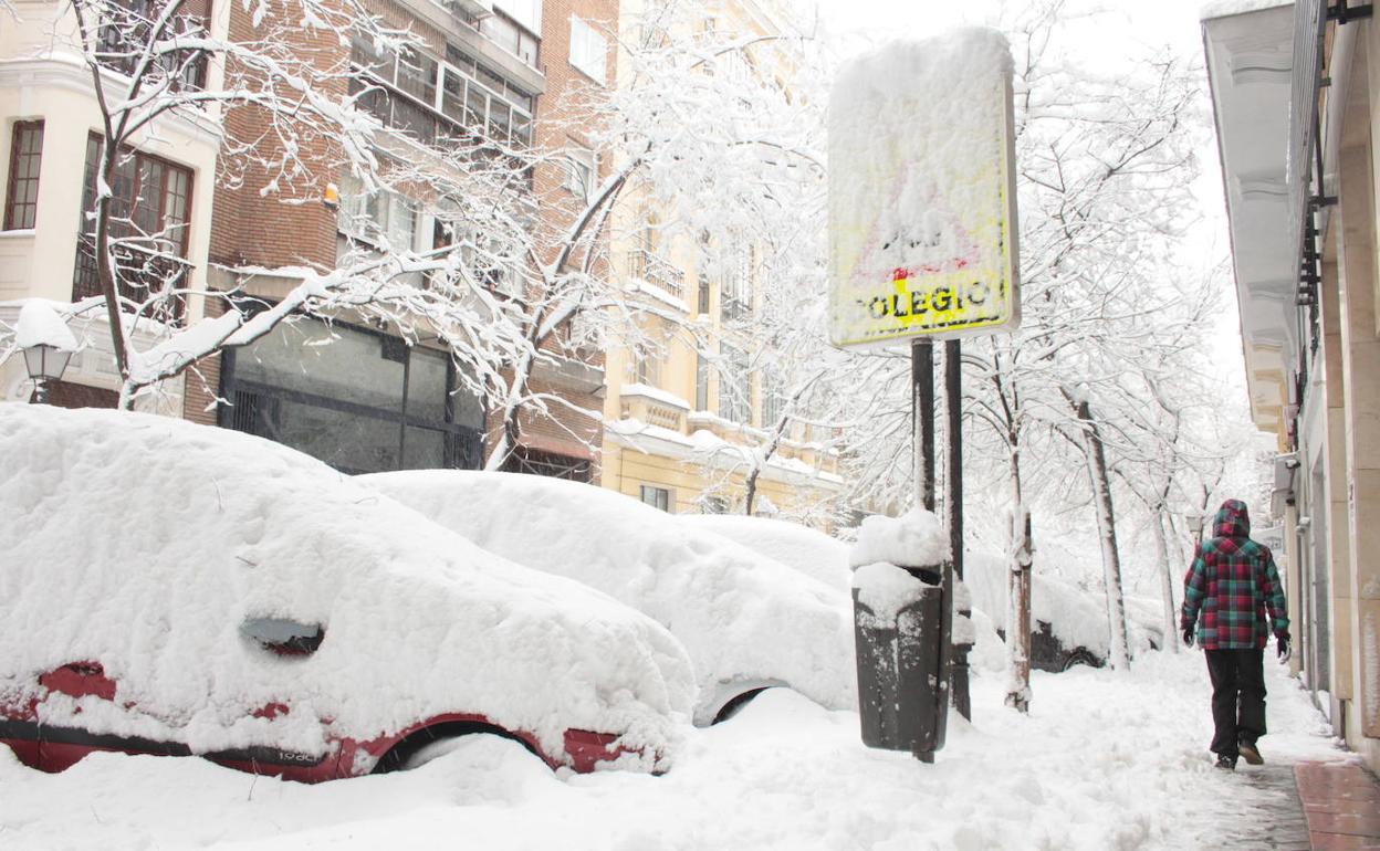 Una señal que indica la ubicación de un colegio tapada por la nieve en Madrid.