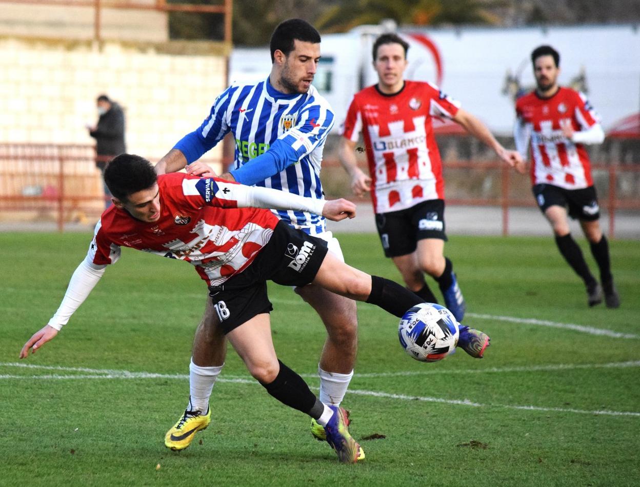 Esteban, a punto de caer en la lucha por un balón con un jugador navarro. 