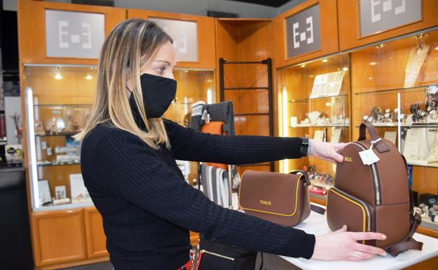 Azucena García coloca bolsos en el expositor de la tienda. 