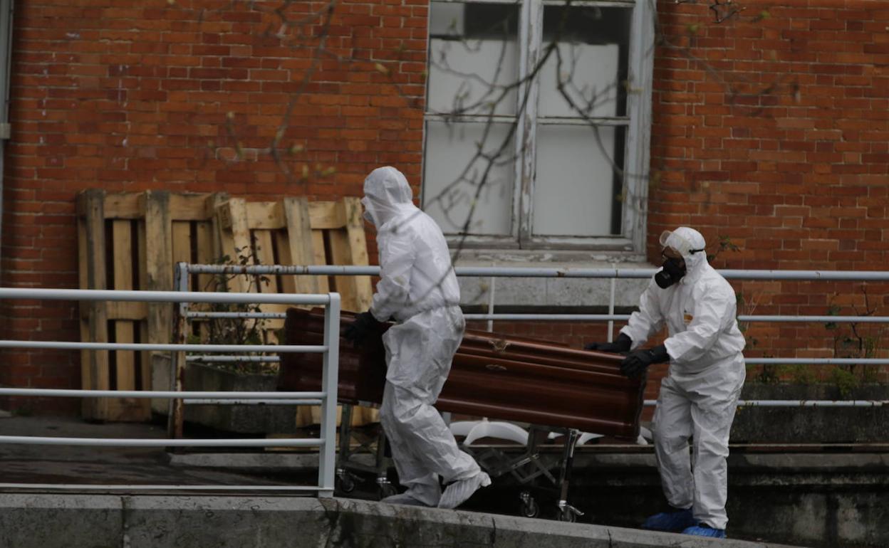 Operarios de una funeraria trasladan un ataúd.