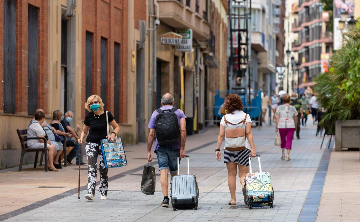 Una pareja de turistas camina por la calle Portales de Logroño portando sus maletas. 