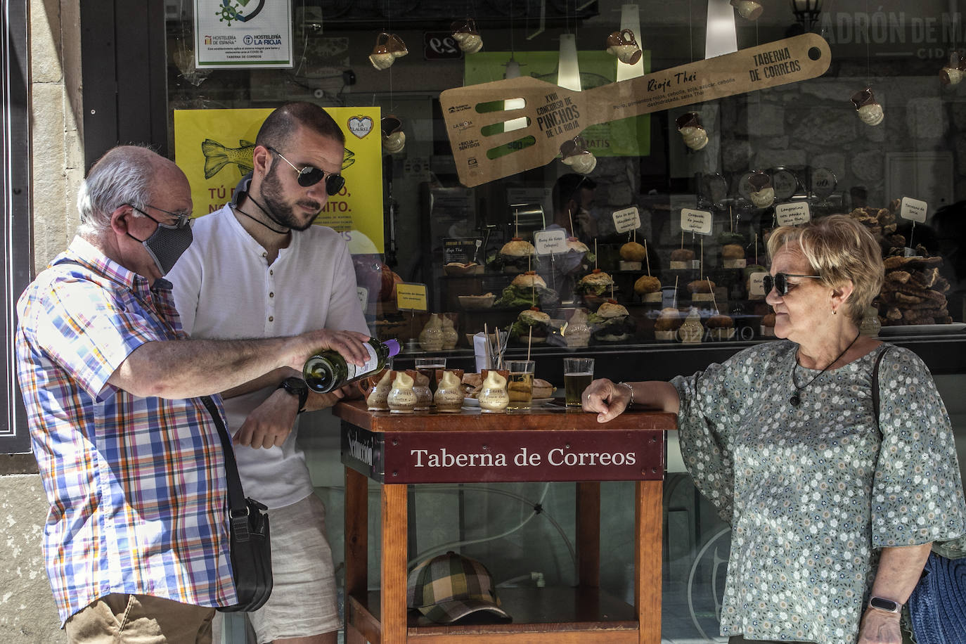 Una familia toma vino en el típico jarrito de San Bernabé, en la calle Laurel. 