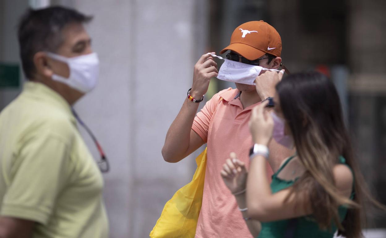 Un hombre se recoloca la mascarillas en la calle.