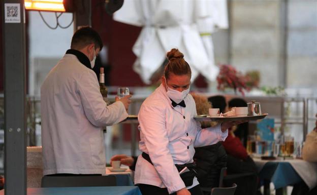 Una empleada de un restaurante sirve en una terraza. 