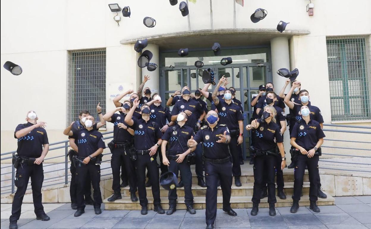 Los nuevos agentes lanzan sus gorras al aire para celebrar su graduación. 