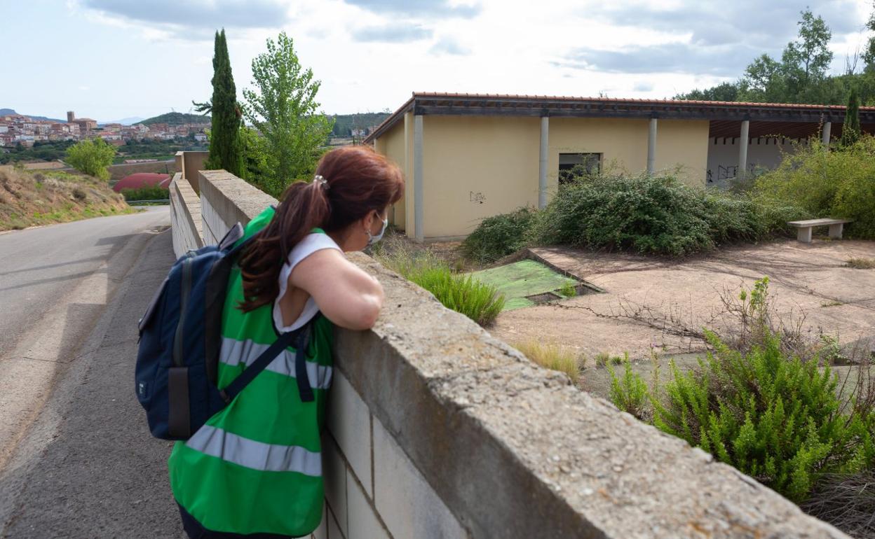 Una mujer observa las abandonadas instalaciones del nuevo cementerio de Entrena, sin uso, con el municipio al fondo. 