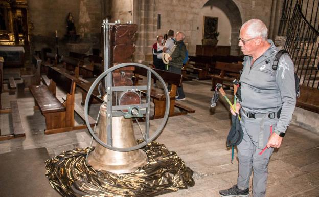 Un peregrino examina la campana de la ermita de Carrasquedo.