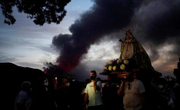 Imagen principal - La procesión de la Virgen del Pino, con el volcán al fondo; El avance la colada norte hasta La Luaguna; y un momento de la erupción de esta noche. 