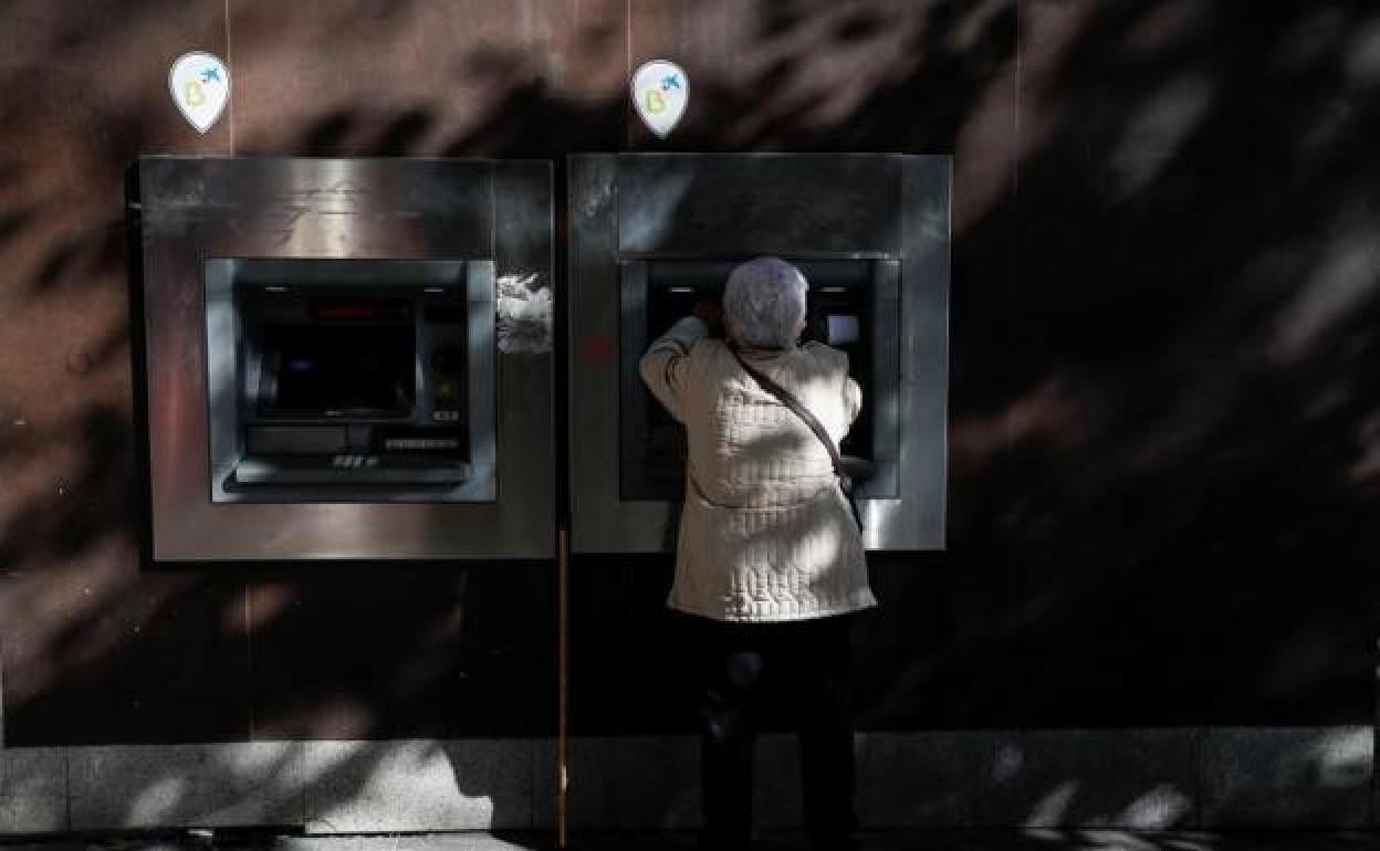 Una mujer saca dinero en un cajero. 