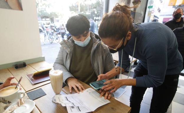 Un cliente muestra su pasaporte COVID en una cafetería vasca. 