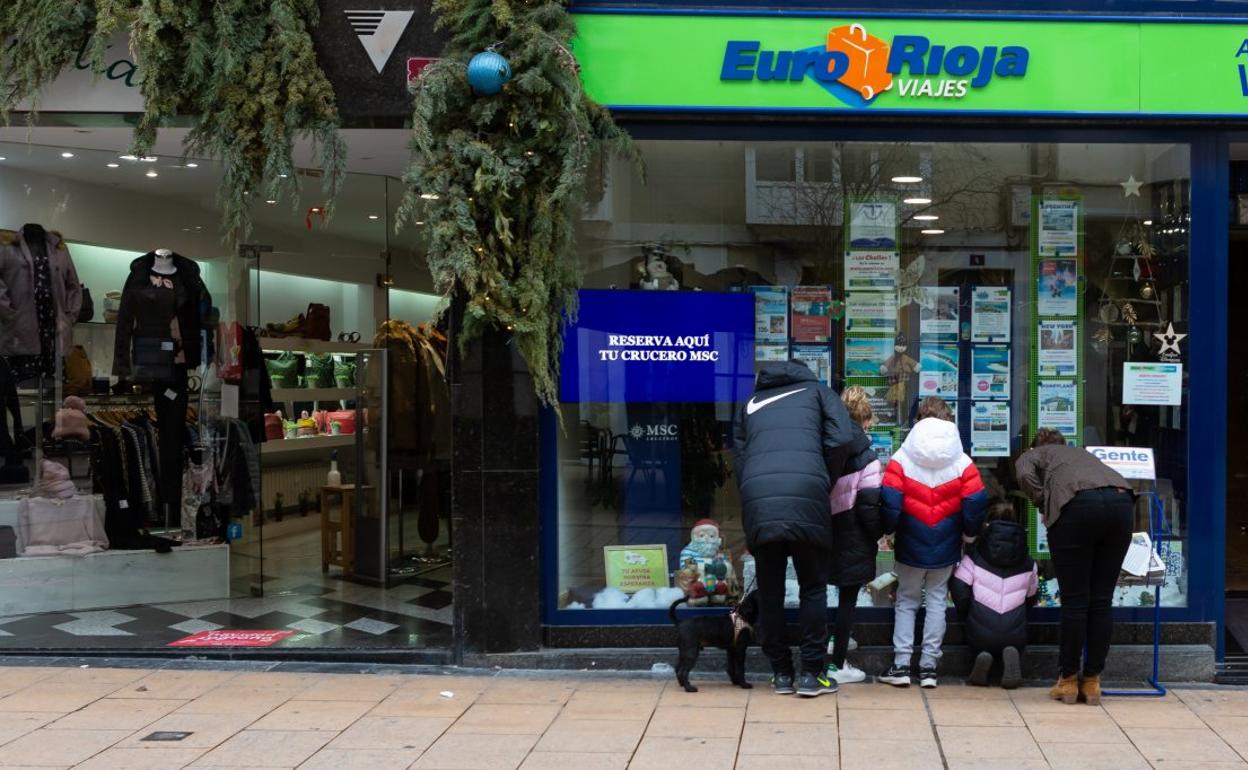 Imagen de archivo de los miembros de una familia observando las ofertas de una agencia de viajes en Logroño. 