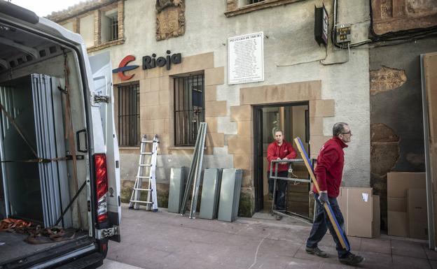 Operarios proceden al desmontaje tras el cierre de la oficina de Ibercaja en Tricio. 