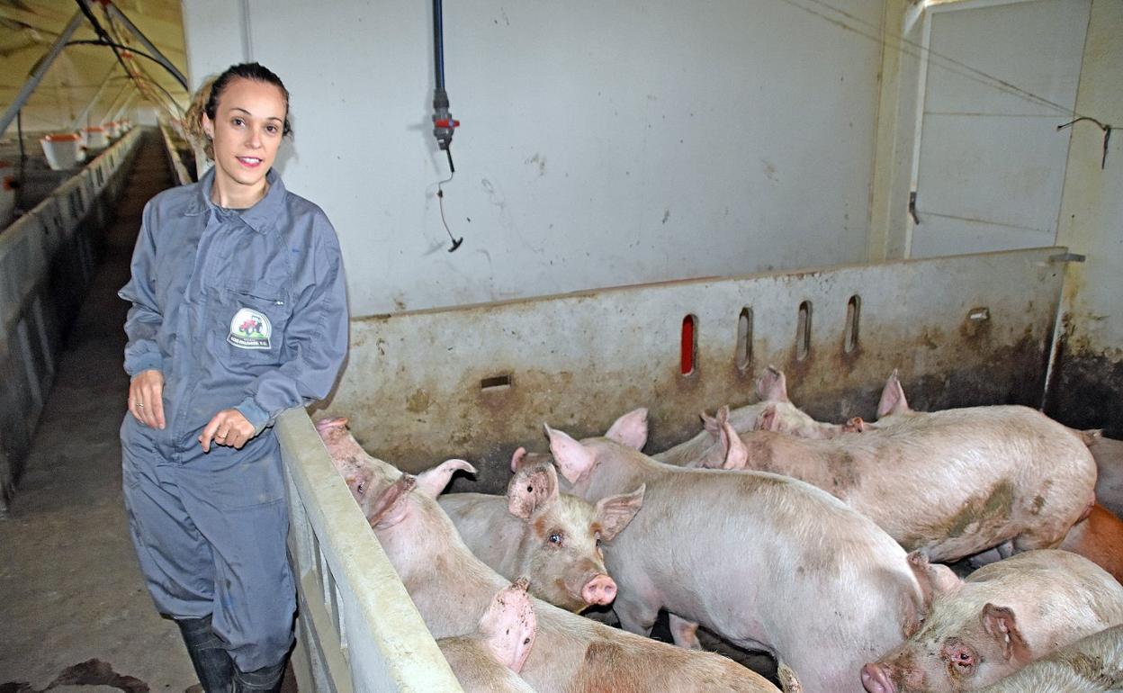 Verónica, con el buzo y las botas, en el interior de una de las naves de su explotación porcina. 