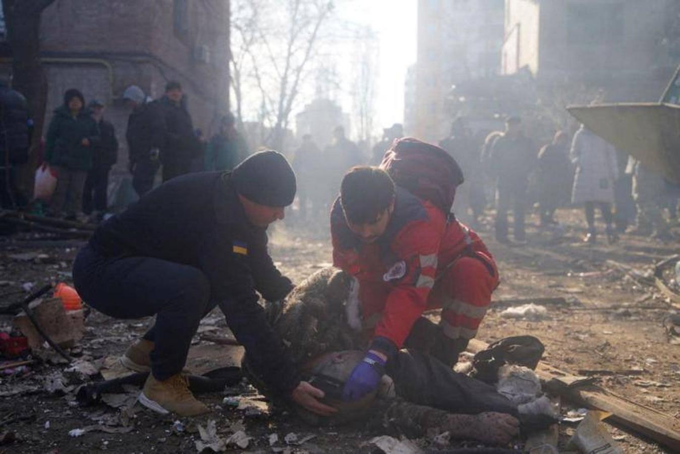 Los rescatistas ayudan a una persona herida junto a los edificios residenciales dañados por los bombardeos.