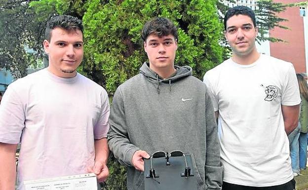 Adrián Somalo, Santiago Sacristán y Roberto Soria posan con su diseño. | Soporte al que han atornillado unas sujecciones para poder limpier los cristales con una mano.