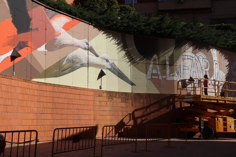 La artista Carolina Hernández Fuentes elabora durante este fin de semana un gran mural en homenaje a la cigüeña detrás de la colegiata. 