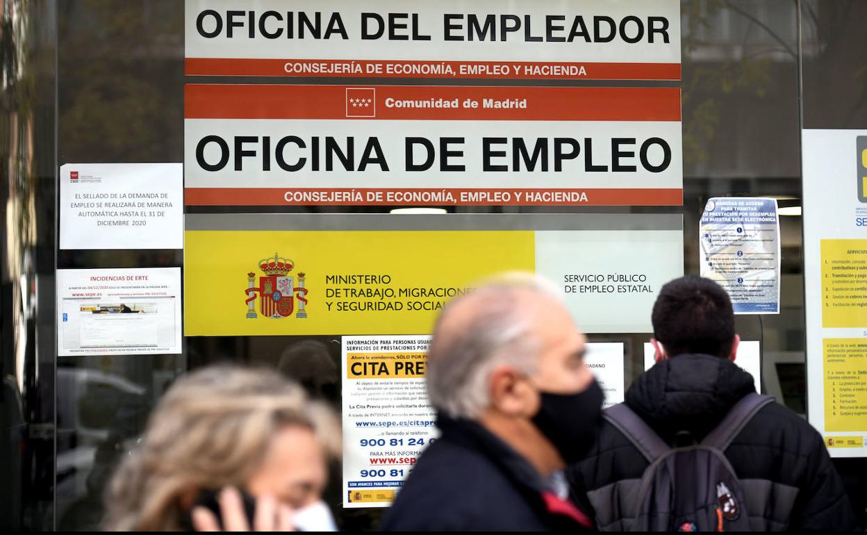 Un grupo de personas hace cola a la puerta de una oficina de empleo.