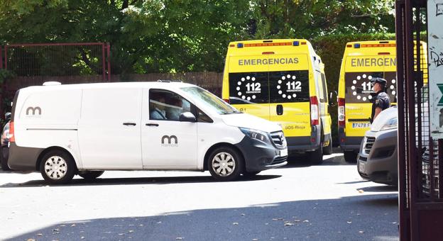 El vehículo de la funeraria y dos ambulancias en el aparcamiento de la urbanización. 