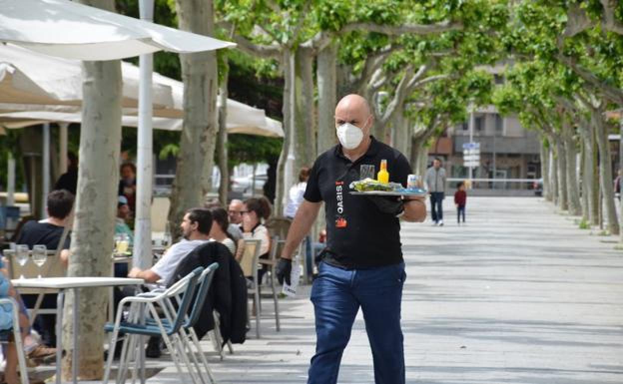 Un camarero sirve una terraza.