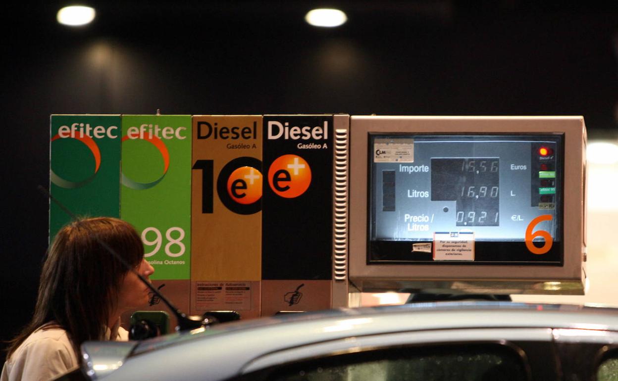 Una mujer en un surtidor de una gasolinera. 