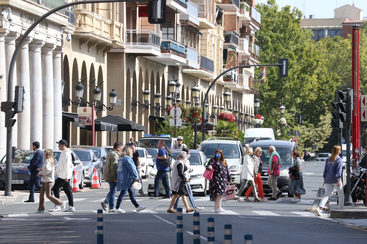 Peatones cruzando uno de los pasos del Espolón con vehículos parados ante uno de los semáforos justo al lado de la Delegación del Gobierno en La Rioja esta misma semana. 