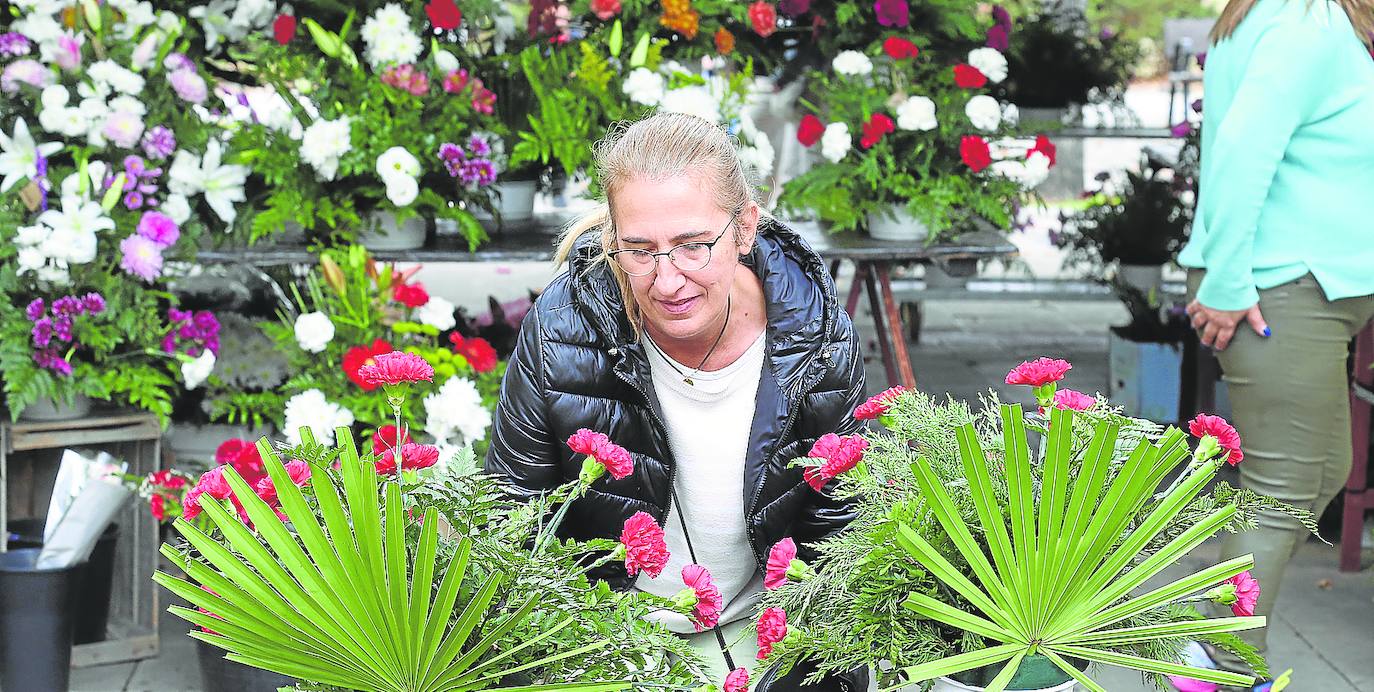 Una mujer sostiene dos centros de flores en el mercado de la plaza Joaquín Elizalde.