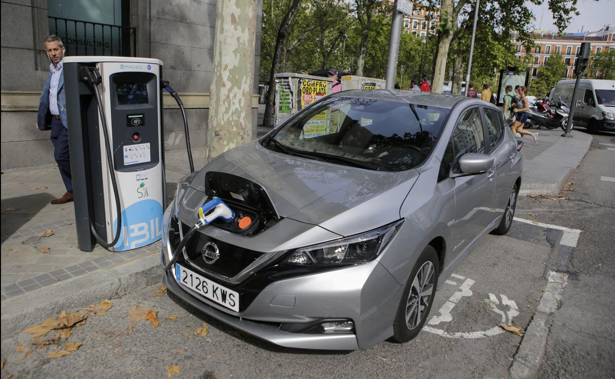 Un vehículo, conectado a un punto de recarga eléctrica. 