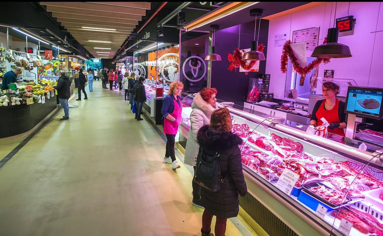 Varias personas comprando carne en un mercado. 