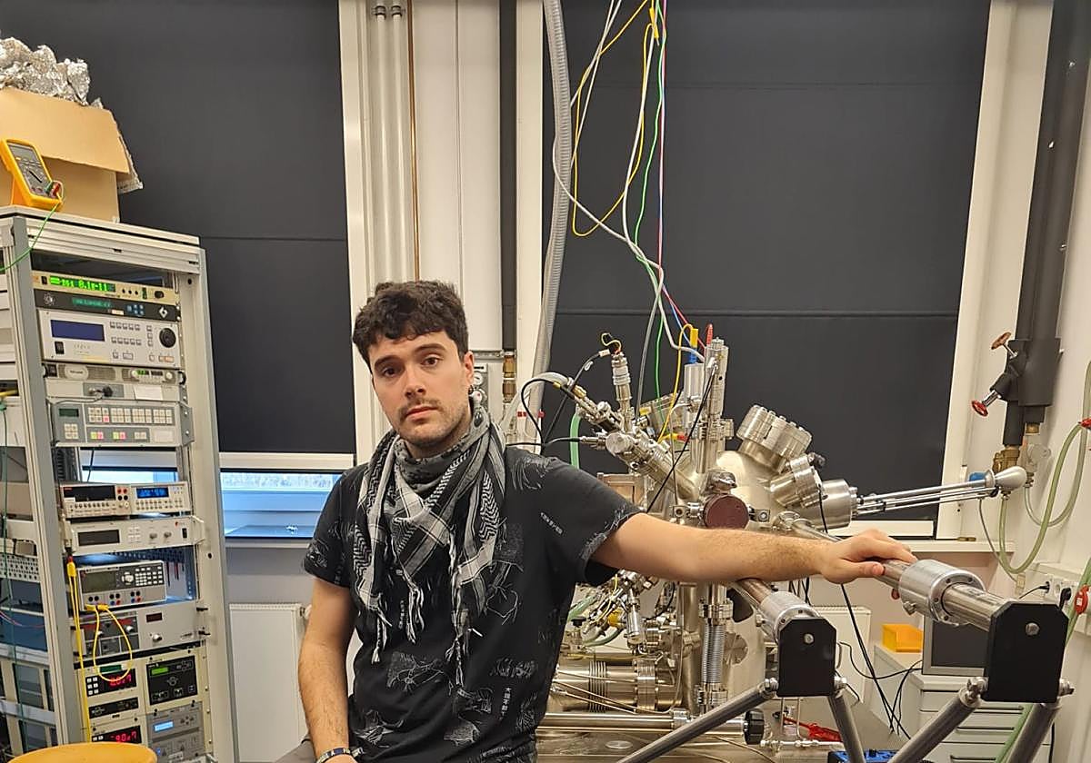 Arturo, con el microscopio que utiliza y sus siglas con átomos.