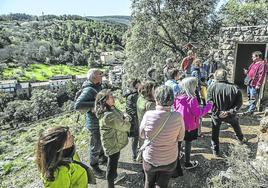 Un grupo de turistas atiende las explicaciones del guía Jorge Martínez antes de acceder a una de las grutas de Ortigosa