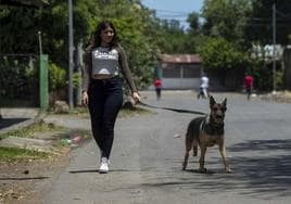 Una joven camina con su perra por una calle de un barrio de Managua