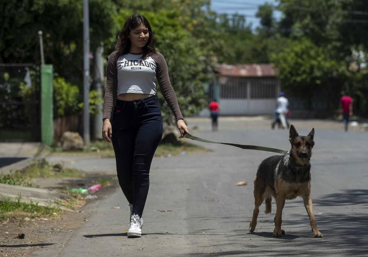 Una joven camina con su perra por una calle de un barrio de Managua