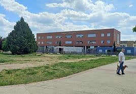 Un hombre pasea a su perro junto al solar municipal en el que se proyecta construir un nuevo parque.