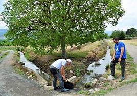 Sergio Ochagavía, agricultor albeldense, observa cómo un regante abre una compuerta en Nalda.